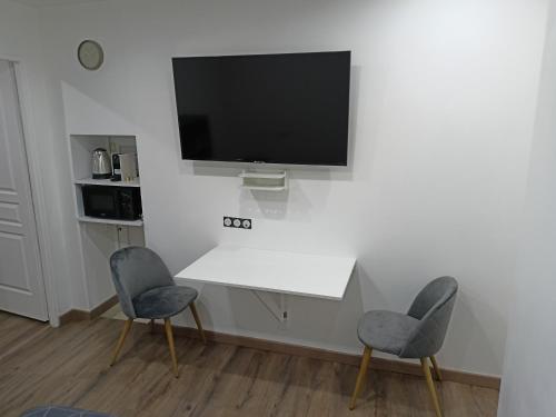 - un salon avec 2 chaises et une télévision murale dans l'établissement Chambre indépendante en plein centre Ville, à Roye
