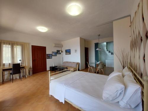 a bedroom with a large white bed and a living room at Horizon Studios with Sea View - Free Parking in Glossa