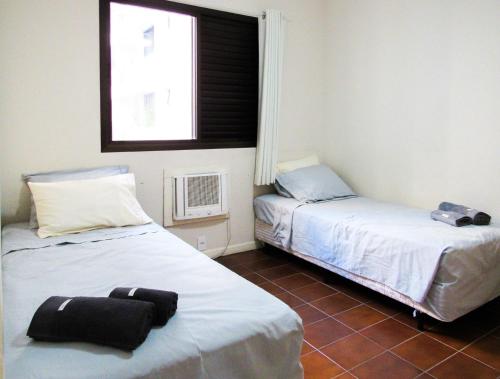 een kamer met twee bedden en een raam bij Otimo Apto a 200m - Praia das Pitangueiras Guaruja in Guarujá