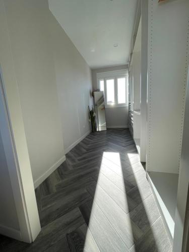 a hallway with white walls and wooden floors and a window at Piso playa Maktub in Puerto Real