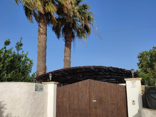 a wooden gate with two palm trees in the background at Le Due Palme in Marsala