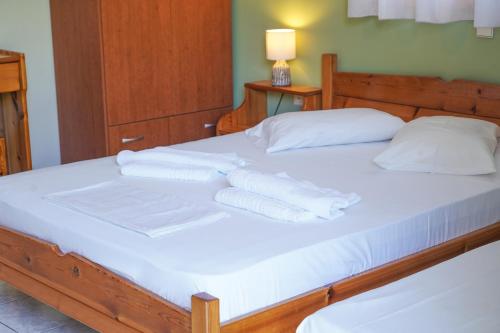 a bed with white sheets and pillows on it at Beach Side Apartments in Dhrepanon