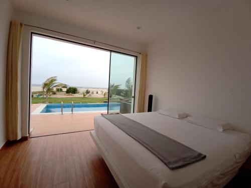 a bedroom with a bed and a large window at Casa VerdeMar Vichayito Perú in Vichayito