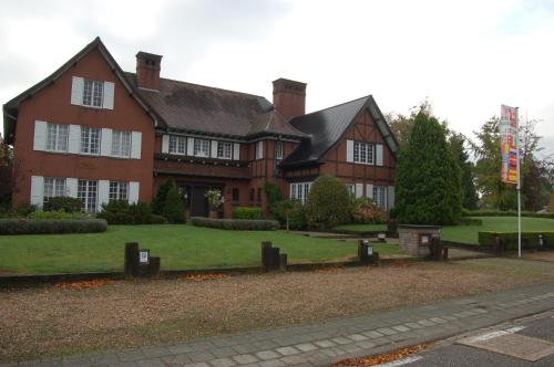 a large red brick house with a green yard at Hotel Ten Lande in Beernem