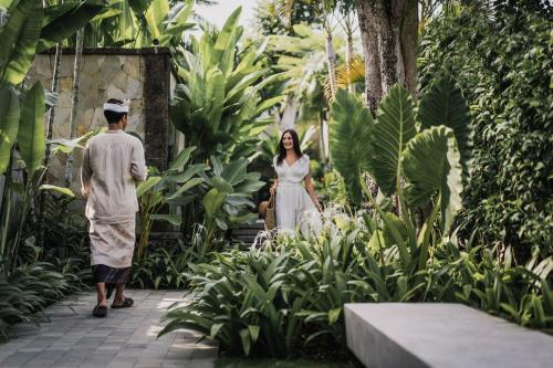 a man and a woman walking through a garden at Kharista Villas & Retreat by Ekosistem in Canggu