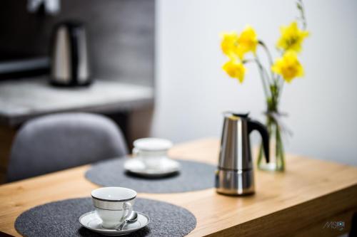 two coffee cups on a wooden table with flowers at Apartamenty Tilia Laskowa - Zator in Laskowa