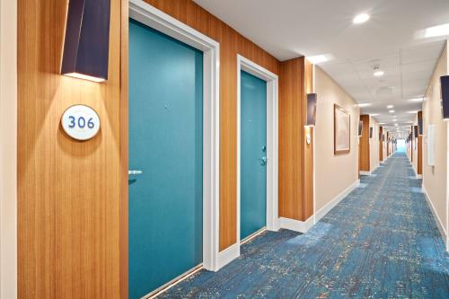 a hallway with blue doors and a sign that says at Compass by Margaritaville Medford in Medford