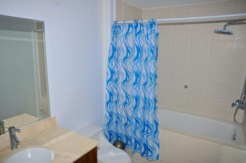 a bathroom with a blue shower curtain with a sink at Condominio 8vo Piso, Jaco Bay in Jacó