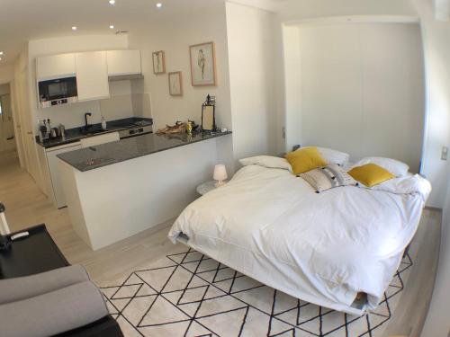 a white bedroom with a bed and a kitchen at Cocoon Paris La Defense in Courbevoie
