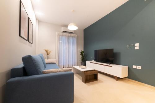 a living room with a blue couch and a tv at IONIS Apartments in Preveza