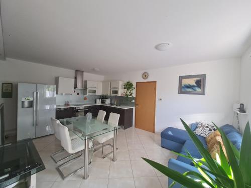 a kitchen and living room with a glass table and chairs at Stanovanje v mirni zeleni okolici in Koper