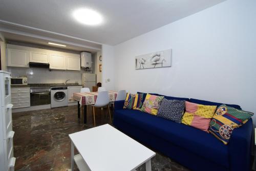 a living room with a blue couch and a kitchen at BENIBEACH - Fincas Arena in Benidorm