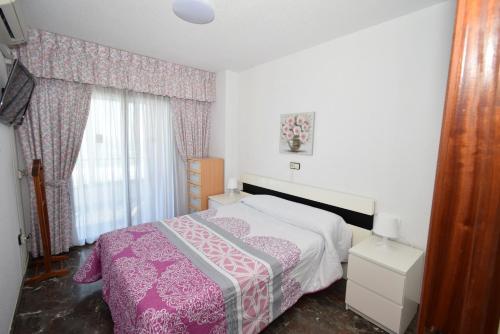 a bedroom with a pink and white bed and a window at BENIBEACH - Fincas Arena in Benidorm