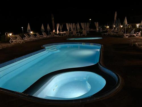 a large blue hot tub at a resort at night at Family Hotel Eterno in Tsigov Chark