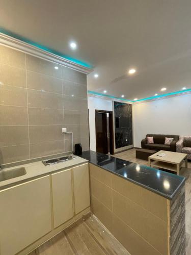a kitchen with a counter top and a living room at تلال الريف in Baljurashi