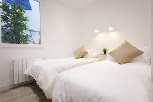two beds in a bedroom with white sheets and a palm tree at Heart of City Centre & Museum by Next Stop Bilbao in Bilbao