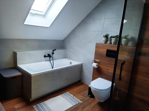 a bathroom with a bath tub and a toilet at Uroczy apartament z dostępnym parkingiem i ogrodem in Szczytniki