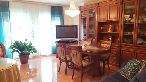 uma sala de jantar com uma mesa e uma televisão em El Santo em Torres