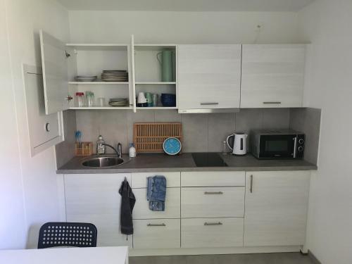 uma cozinha com armários brancos, um lavatório e um micro-ondas em Studio "Minergy" em Donatyre