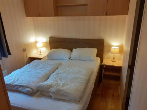 a bed with white sheets and pillows in a bedroom at Stellechalets op Vakantiepark Stelleplas - Heinkenszand in Heinkensand