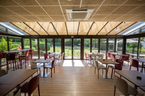 une salle à manger avec tables, chaises et fenêtres dans l'établissement Kyriad Blois Sud - Vineuil, à Vineuil