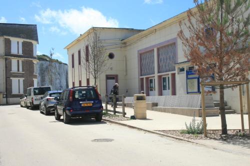 a building with cars parked on the side of a street at escapade en mer in Ault