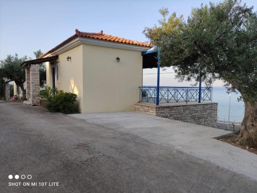 a small white building with a blue gate next to the ocean at Iliadis Vacation Homes in Petalidi