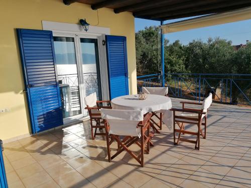 una mesa y sillas en un patio con persianas azules en Iliadis Vacation Homes en Petalídhion