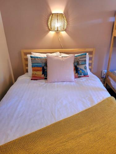 a white bed with pillows and a light on the wall at Motel Abricafé in Stoneham
