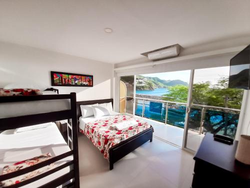 a bedroom with a bed and a large window at Hostal Viña del Mar in Taganga