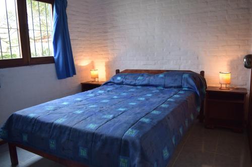 1 dormitorio con 1 cama azul y 2 lámparas en Bungalows Costa Esmeralda en La Paloma