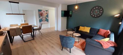a living room with a couch and a table and a clock at Gailtaler Apartments Alinkhof in Bach