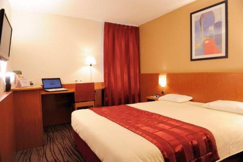 una habitación de hotel con una cama y un ordenador portátil en un escritorio en Kyriad Evreux - Netreville, en Évreux