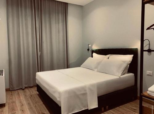 a bedroom with a bed with white sheets and pillows at Merly Hotel in Përmet