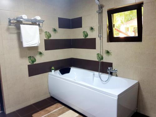 ein Bad mit einer weißen Badewanne und einem Fenster in der Unterkunft Cazare la munte Comarnic in Comarnic