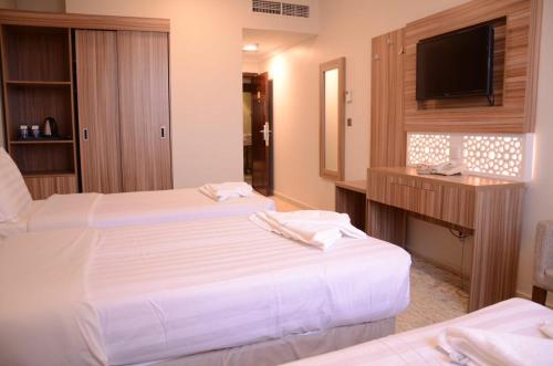 a hotel room with two beds and a flat screen tv at Artal Taiba Hotel in Al Madinah
