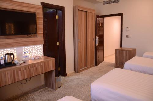 a hotel room with two beds and a flat screen tv at Artal Taiba Hotel in Al Madinah