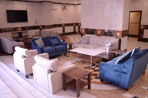 a living room with couches and tables and a tv at Artal Taiba Hotel in Al Madinah