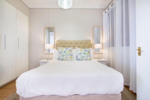 a white bedroom with a large white bed with two lamps at Durban Point Waterfront, 805 Quayside 40 Canalquay Rd in Durban