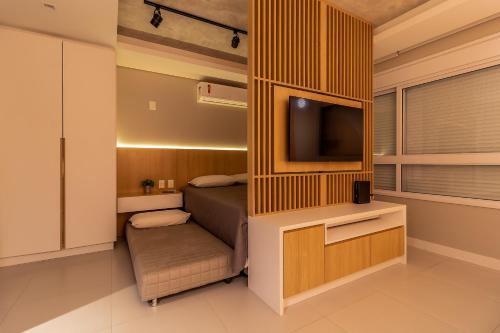 a small bedroom with a bed and a television at StudioTerraCor-Novo apto Jurere 240m da praia in Florianópolis