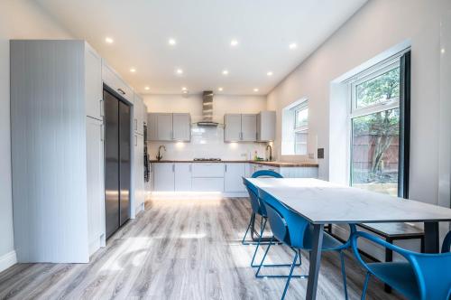 a kitchen with a dining table and blue chairs at The Manor - Large Luxury home in Bournemouth - Sleeps 12+ in Bournemouth