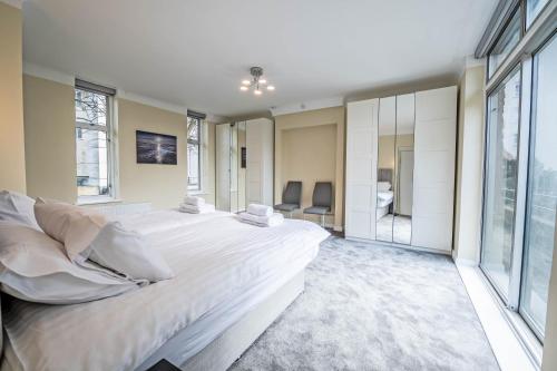 ein großes Schlafzimmer mit einem großen Bett und großen Fenstern in der Unterkunft The Manor - Large Luxury home in Bournemouth - Sleeps 12+ in Bournemouth