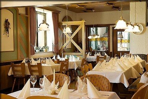 un comedor con mesas y sillas blancas en Hotel Bayerischer Hof en Lindenberg im Allgäu