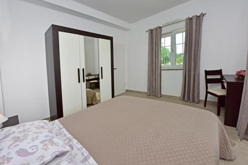 a bedroom with a bed and a desk and a window at Apartman Melita in Poreč