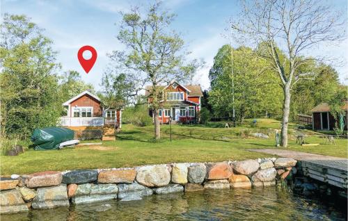 a house with a red marker in front of a river at Lovely Home In Gräddö With Sauna in Gräddö