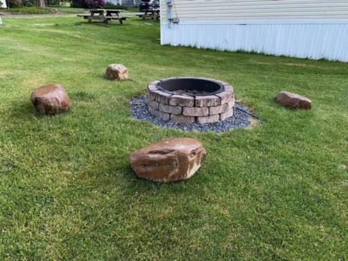 a fire pit in the grass with rocks around it at Stay In Ohiopyle - closest place to the GAP trail in Ohiopyle, PA, Hot Tub in Ohiopyle