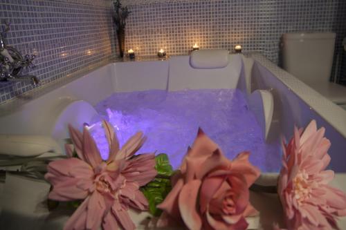 une baignoire remplie d'eau violette et de fleurs roses dans l'établissement Apartamentos Rurales Las Dos Torres, à Isla
