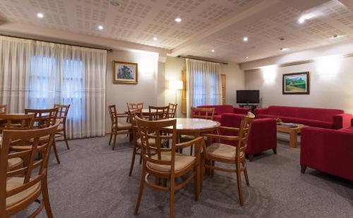 una sala de espera con mesas, sillas y TV en Hotel Herradura, en Santiago de Compostela