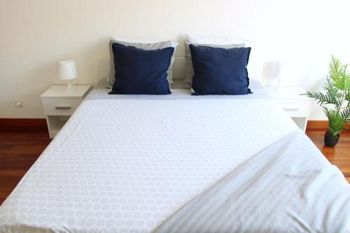 a white bed with blue pillows in a bedroom at Cozy apartment with Free Parking & close to Lake in Lugano