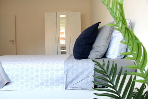a bed with blue and white pillows and a plant at Cozy apartment with Free Parking & close to Lake in Lugano